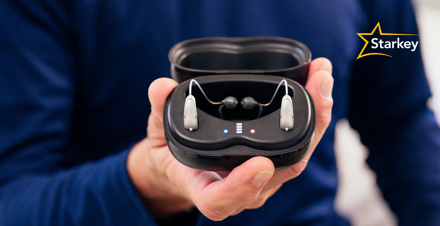 Image of male holding open charging case with hearing aids inside
